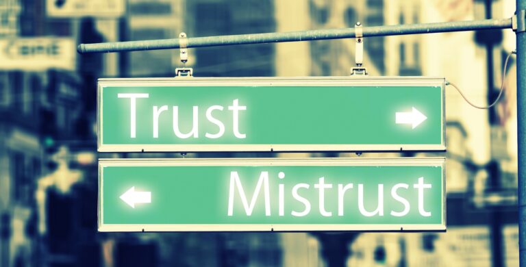 Two street signs: one says "Trust" with an arrow pointing to the right and the other says "Mistrust" with an arrow pointing to the left.